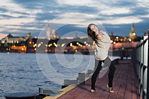 A young woman stands on the waterfront against evening the city