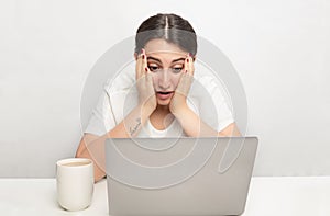 Young woman staring at a laptop in disbelief