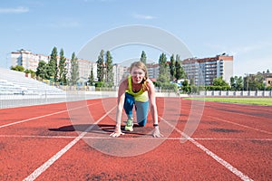 A young woman in the starting position for running on a sports track