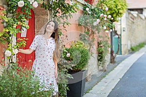 Young woman staying near red door on the street in old town