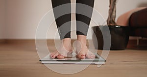 Young woman stepping on scale and wiggling her toes while checking her weight