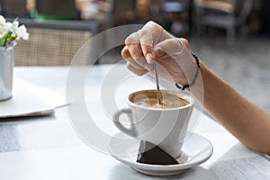 Young woman stirring a coffee