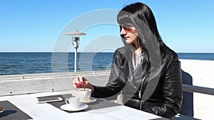 Young woman stirring  coffee with a teaspoon in an outdoor cafe