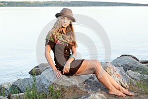 Young woman on stones near water