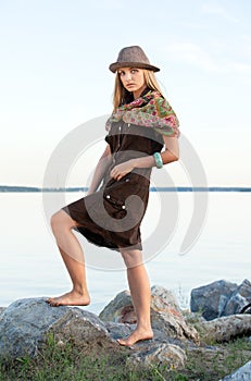 Young woman on stones near water