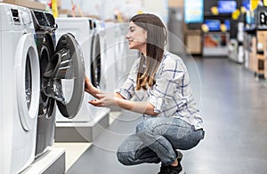 A young woman in a store chooses a washing machine