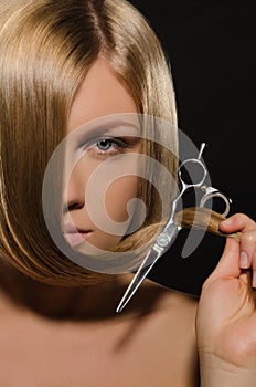 Young woman with straight hair holds scissors