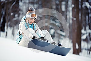 Young woman strapping on Snowboard