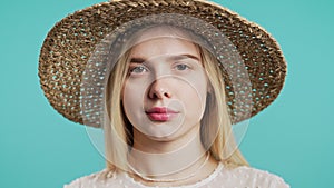 Young woman in straw hat disapproving no head sign,nods disapprovingly on blue