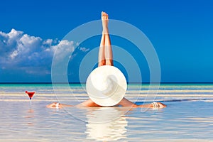 Mujer joven en paja un sombrero mintiendo sobre el Playa a feliz cóctel 