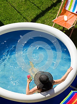 Young woman in a straw hat relaxing in the garden pool