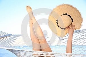 Young woman with straw hat resting in hammock