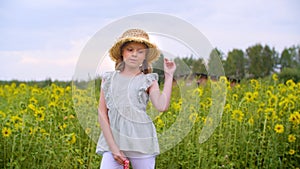 Young woman in straw hat with sunflowers posing on flowering field landscape. Cute rural girl standing on bloowing