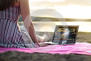 Young woman streaming a movie with laptop computer on beach.