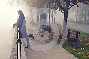 Young woman on the street on foggy autumn day