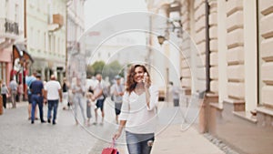 Young woman at the street with shopping bags talking on mobile phone