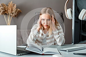 Young woman in stress do office work via pc laptop. Tired young woman with Headache Due to deadline Overtime problem