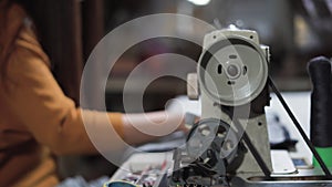 young woman stretches a turn towards the volcano and uses an old sewing machine in a sewing workshop. Small business