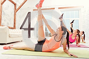 Young woman stretching with friends at gym.