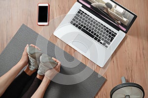 Young woman stretching at home while watching yoga class online