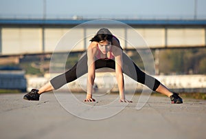 Young woman stretching leg muscles with hands on floor