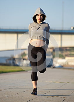 Young woman stretching leg muscles outdoors