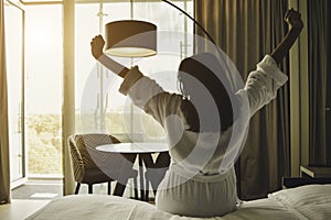 Young woman stretching in the morning in a hotel room and looking at the sunrise.