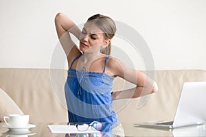 Young woman stretching suffering from sudden back pain, feeling