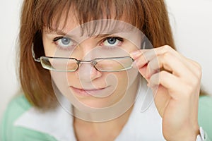 Young woman strictly looks over spectacles