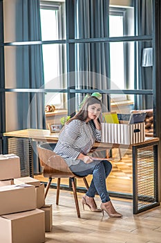 Young woman in a striped jacket sitting on the chair and feeling uncertain