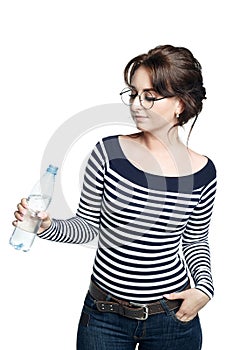 A young woman in a striped tight blouse holds in her right hand a bottle with clean drinking water