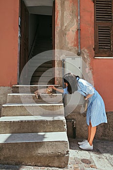 Young woman stroking a cat on the Italy street