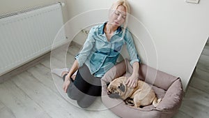 Young woman stroking her dog sitting on the floor.