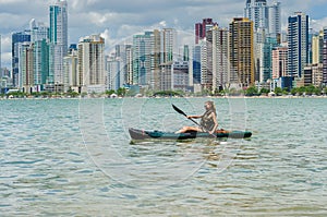 Young woman strolling by kayak on Brazilian beach. Fishing kayak