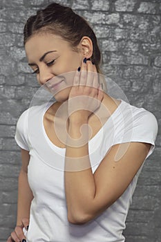 Young woman struggles with neck pain, hand in the place of pain