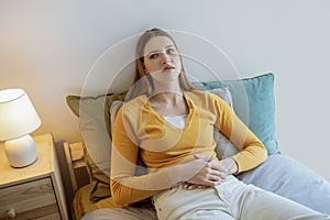 Young Woman Struggling With Menstrual Cramps And Pain Lying Indoors