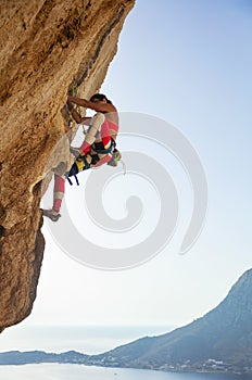 Young woman struggling to climb challenging route