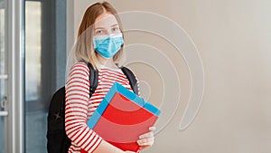 Young woman student in protective medical mask. Portrait of blonde female student Girl at university interior during coronavirus