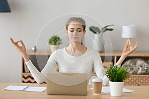 Young woman student taking break meditating at home office desk