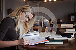 Young woman student of the University. Preparing exam and learning lessons in public library.