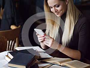 Young woman student of the University. Preparing exam and learning lessons in public library.