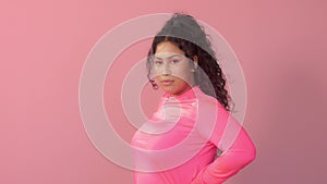 Young woman in studio on pink wears a neon turtleneck and neon makeup