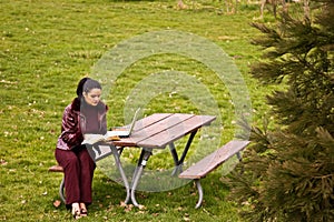 Young Woman Studying at Park with Laptop