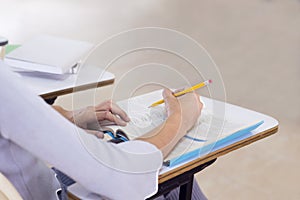 Young woman studying for a test, student hands writing in book at classroom. Learning and Education, college concept