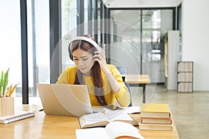 Young woman studying or working online using laptop and wearing headphones.