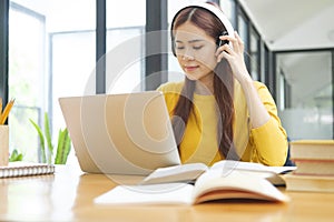 Young woman studying or working online using laptop and wearing headphones.