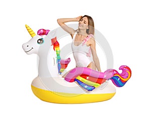 Young woman in stylish bikini with  unicorn inflatable ring on white background