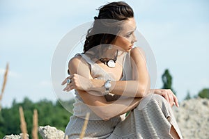 Young  woman with stylish silver jewelry sitting on the sand