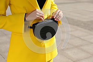 Young woman with stylish waist bag outdoors, closeup