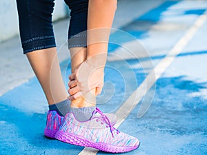 Young woman suffering from an ankle injury while exercising and running.